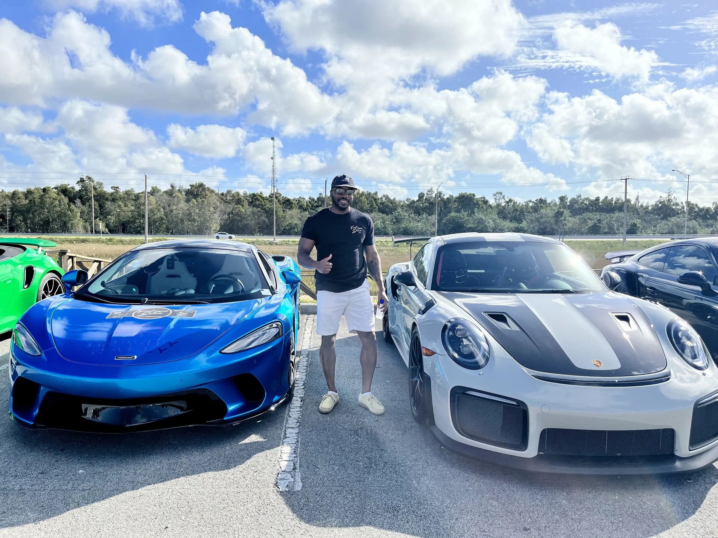 Mario G Bee standing between two sports cars at a car event