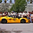 Rally participants in matching Motivation Rally shirts lined up behind a yellow Lamborghini wrapped with the rally crest